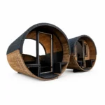 Twee ronde houten buitensauna's met donker shingledak; de voorste heeft een gebogen panoramaglazen front met centrale glazen deur en de achterste een houten front met deur en twee smalle ramen, op witte achtergrond.