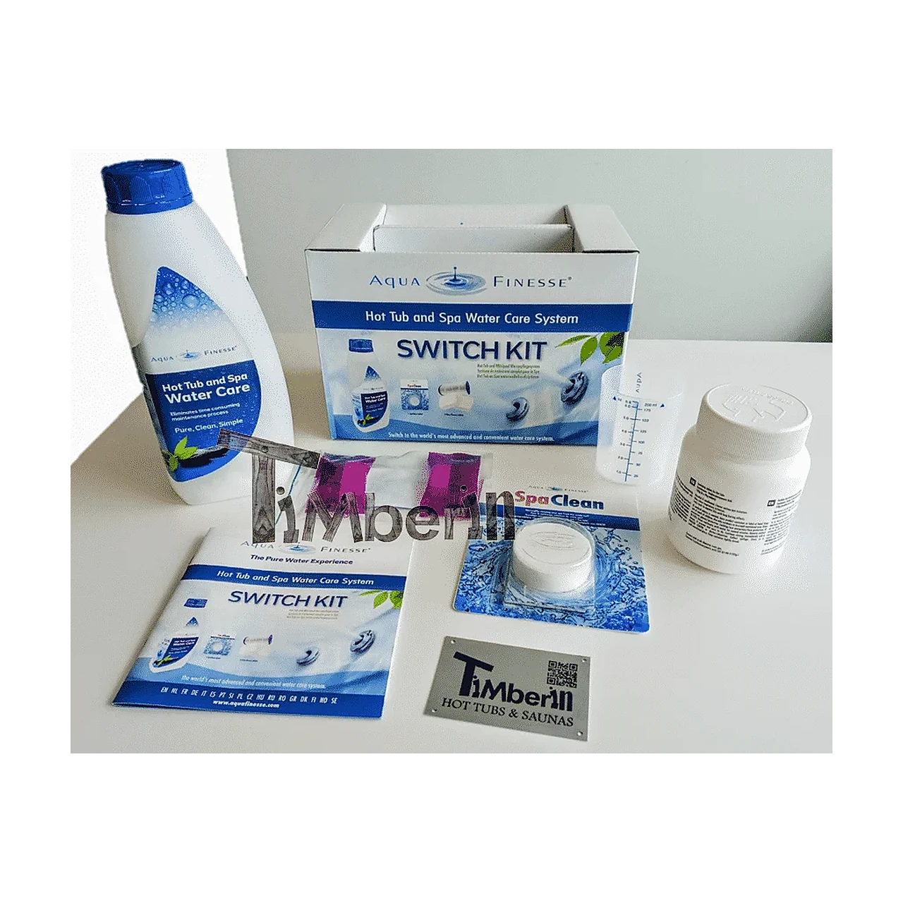 Onderdelen van een AquaFinesse hottub-waterverzorgingsset, waaronder een fles, Switch Kit-doos en handleiding, maatbeker, witte pot, SpaClean-tablet en TimberIN-plaatje op witte achtergrond.