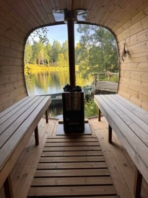 Interieur van de TimberIN Nordic Square mobiele sauna met houten banken en houtkachel aan een meer