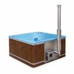 TimberIN Nordic Elite Square grote vierkante houtgestookte hottub met blauwe kuip, houten bekleding, donkere zijpanelen, geïntegreerde roestvrijstalen kachel en hoge schoorsteen op witte achtergrond.