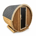 Compacte ronde houten buitensauna met donkergrijs shingledak, hoge glazen deur, licht houten deurkader, metalen spanbanden en rechthoekige houten voet op witte achtergrond.