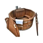 Ronde volledig houten hottub van donker thermohout met geopende tweedelige houten afdekking, houten binnenbanken, afgeschermde interne houtkachel, hoge schoorsteen en witte handdoek op witte achtergrond.