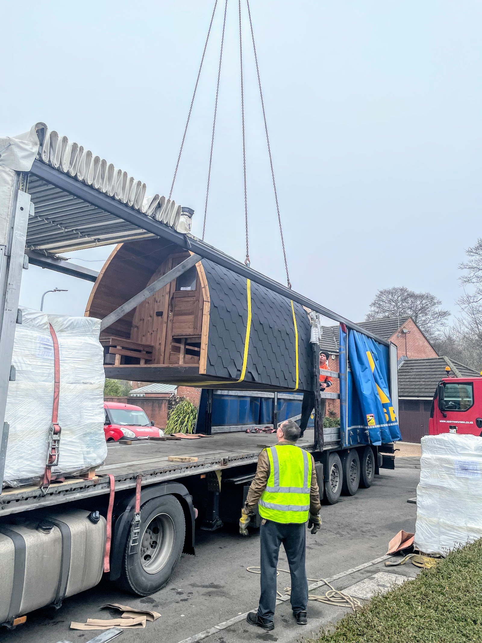 Barrelsauna wordt met een kraan van de vrachtwagen getild