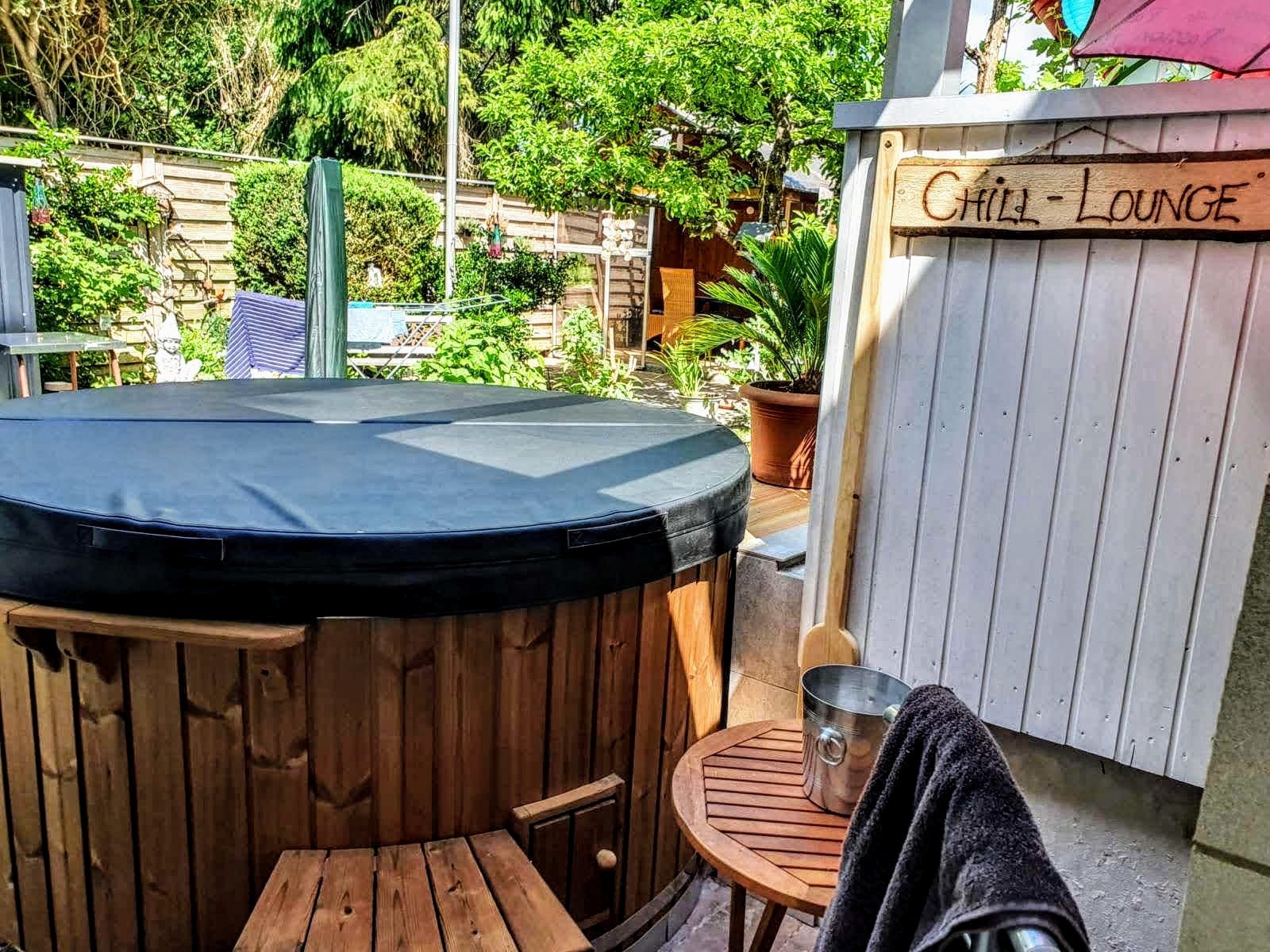 Afgedekte hottub op een terras naast tuinmeubelen