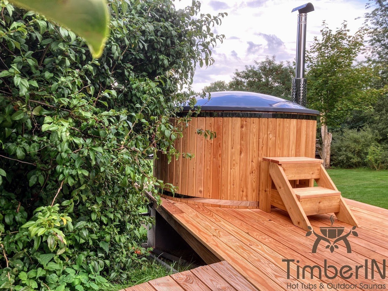 Ronde hottub met lariks bekleding in warme tinten en houten trap