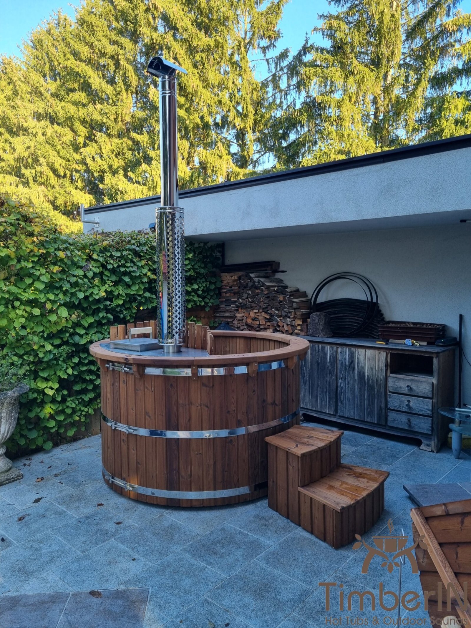 Ronde hottub van bruin thermisch gemodificeerd hout met houten trap op een terras