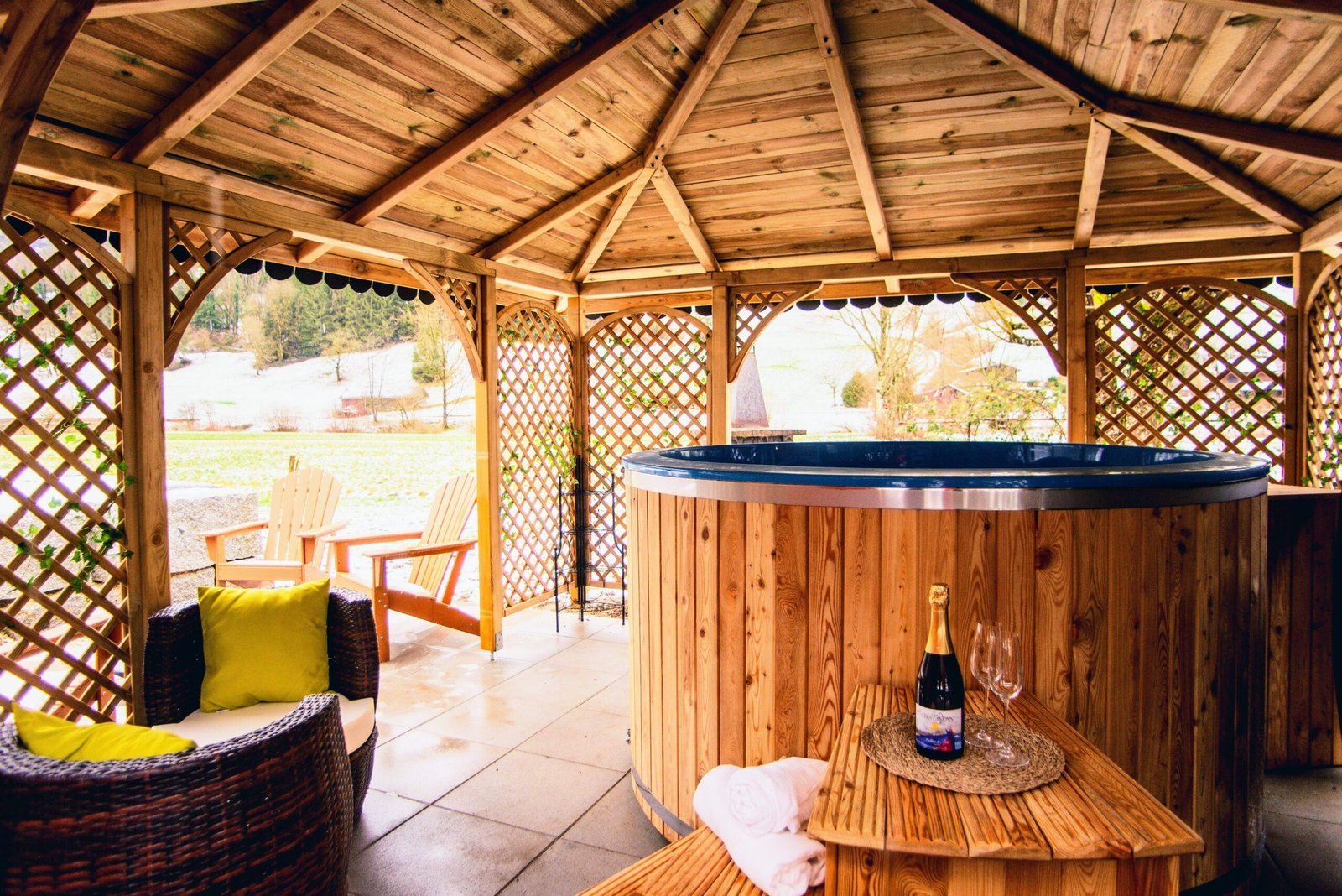 Hottub en zitplek onder een houten overkapping in een tuin