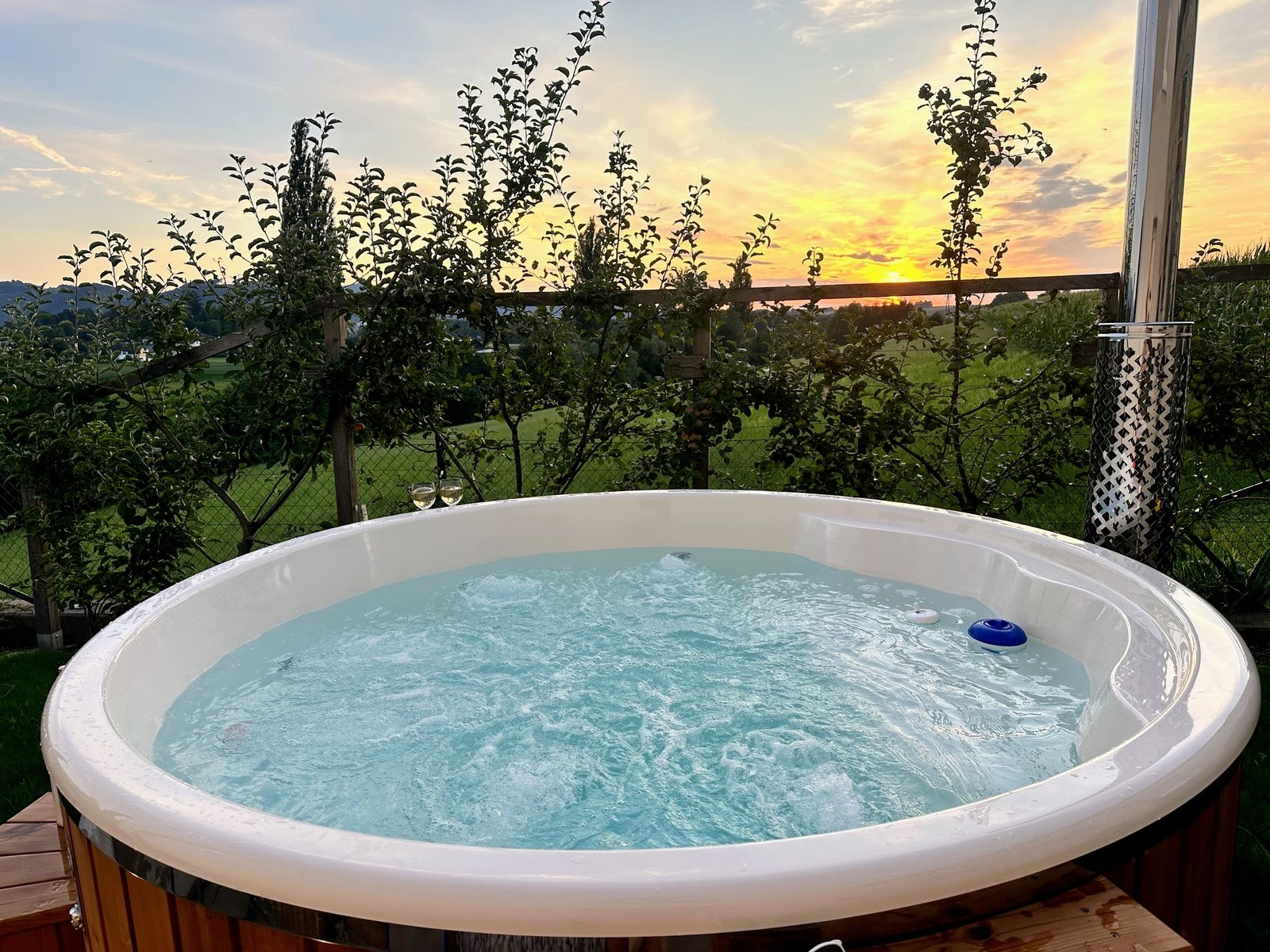 Ronde hottub met gladde binnenkuip in een tuin bij zonsondergang