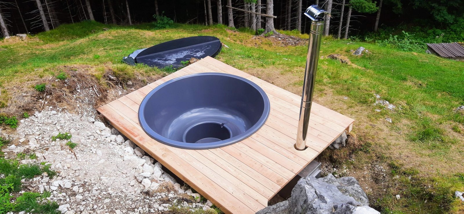 Ronde grijze hottubkuip ingebouwd in een houten ombouw