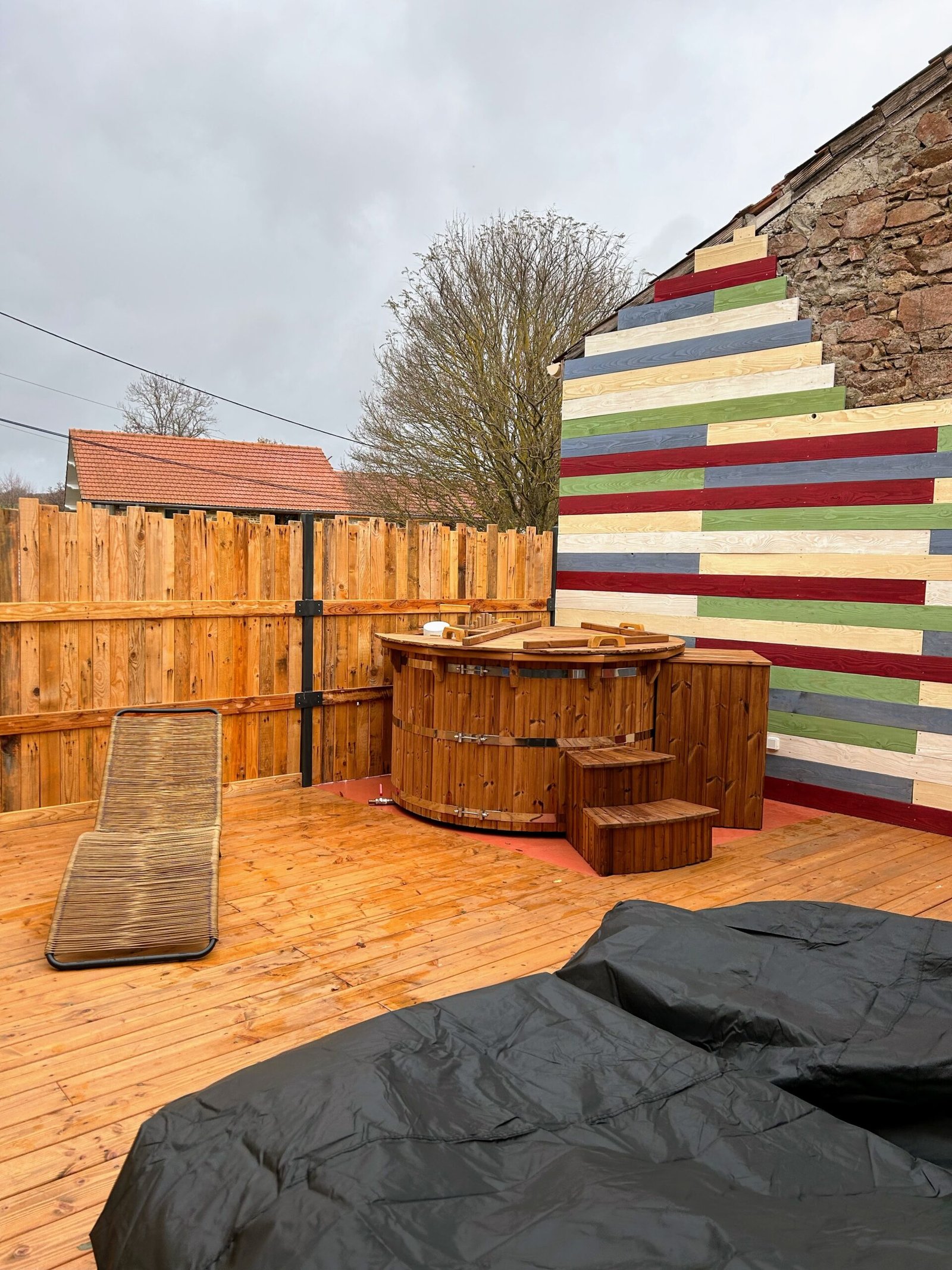 Afgedekte houten hottub met trap op een omheinde tuinvlonder
