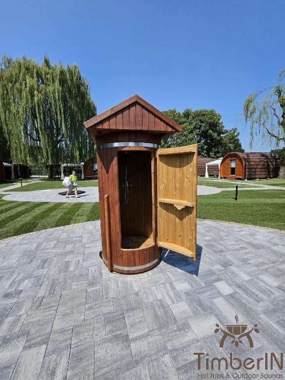 Houten barrel-buitendouche met open deur in de tuin