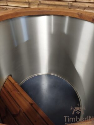 Bovenaanzicht van de lege rvs binnenkuip van het TimberIN Icetub-koudwaterbad, met geborstelde metalen wand, ronde bodem en donkere houten zitstap onderaan