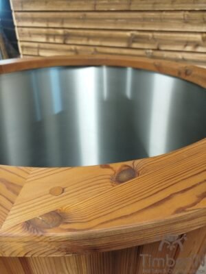 Close-up van de brede thermohouten rand van het TimberIN Icetub-koudwaterbad, met duidelijke nerf, zichtbare kwastgaten en blanke rvs binnenkuip