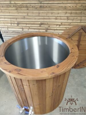 Verhoogd aanzicht van het open TimberIN Icetub-koudwaterbad, met blanke rvs binnenkuip, brede thermohouten rand, twee aftapkranen en houten afdekking op de achtergrond