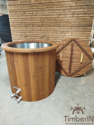 Vooraanzicht van het compacte TimberIN Icetub-koudwaterbad in een werkplaats, met rvs binnenkuip, thermohouten bekleding, twee aftapkranen en een tegen het bad geplaatste gesegmenteerde afdekking