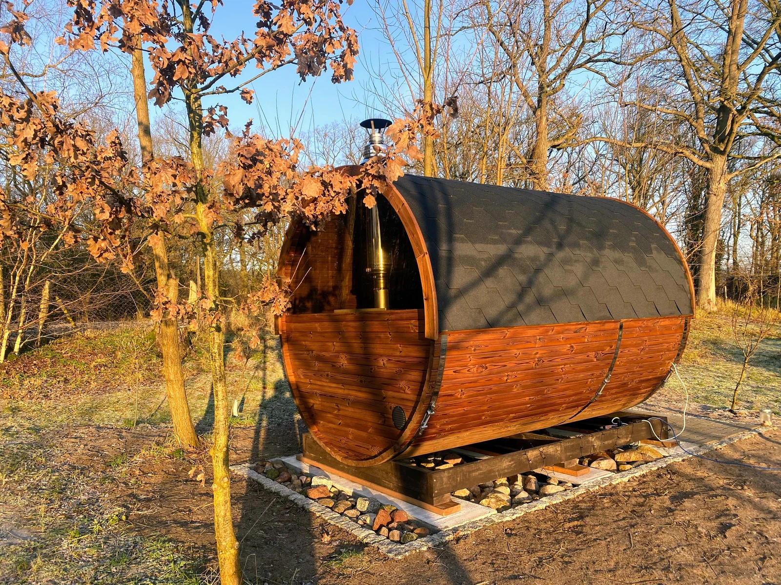 Houten horizontale barrel sauna bij bomen met herfstkleuren