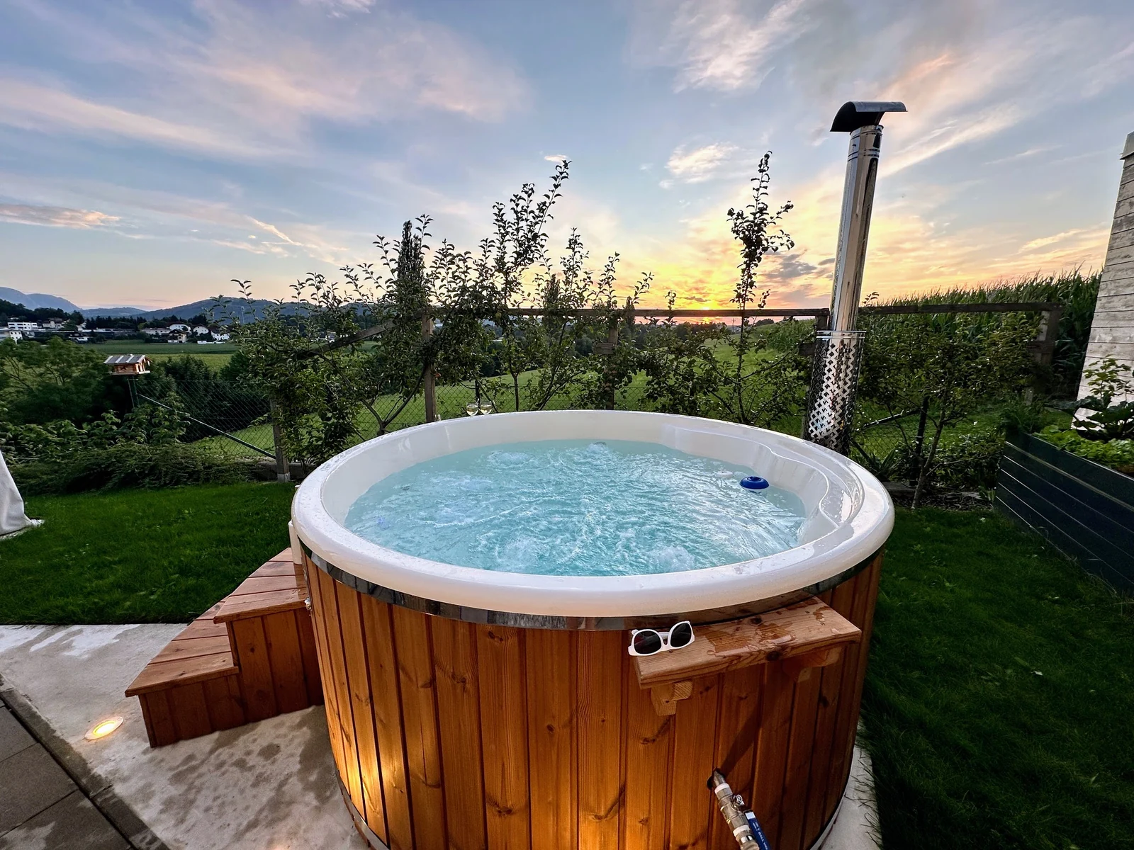 Ronde hottub met lichte binnenkuip in een tuin bij zonsondergang