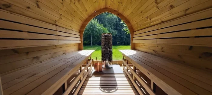 Houten sauna-interieur met banken, kachel en uitzicht op de tuin