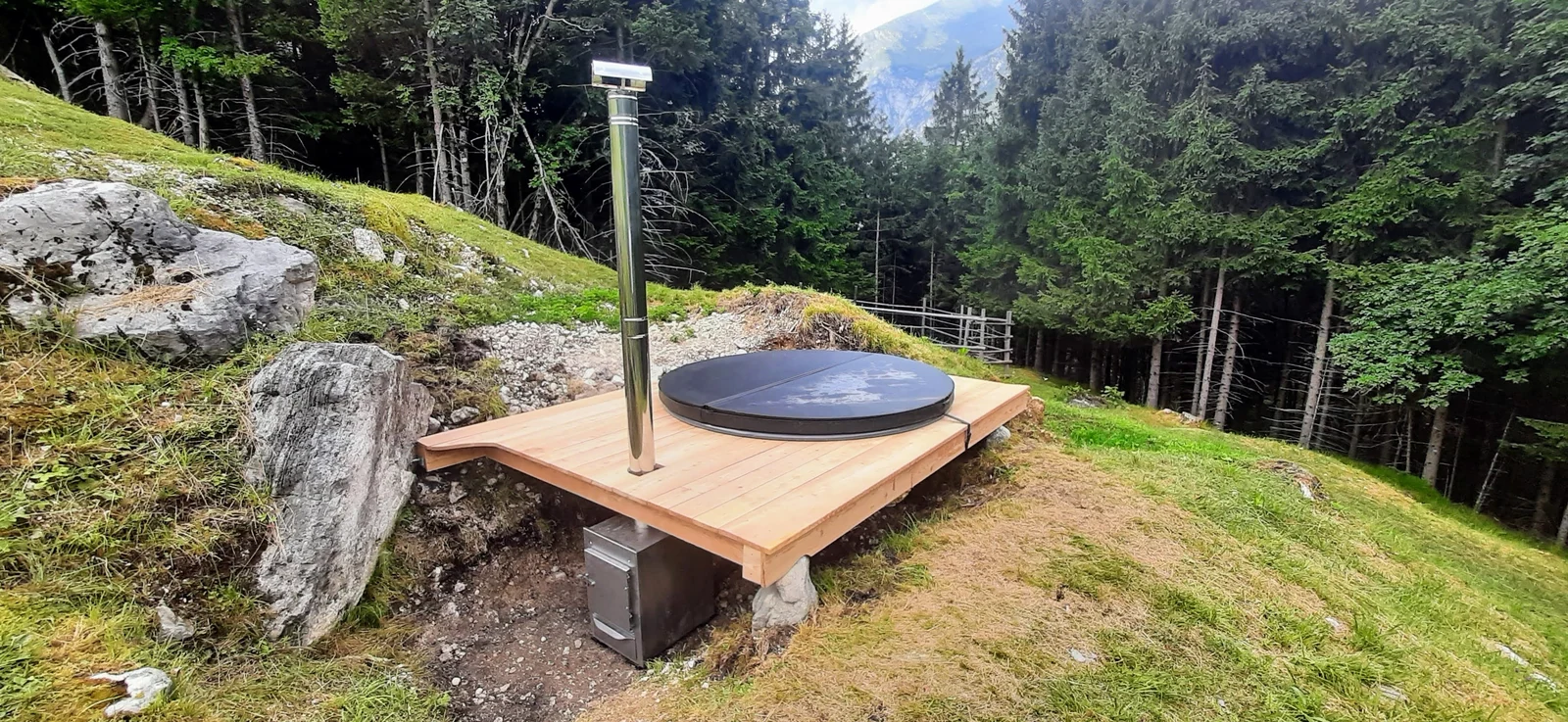 Afgedekte hottub verwerkt in een houten terras tussen de bomen