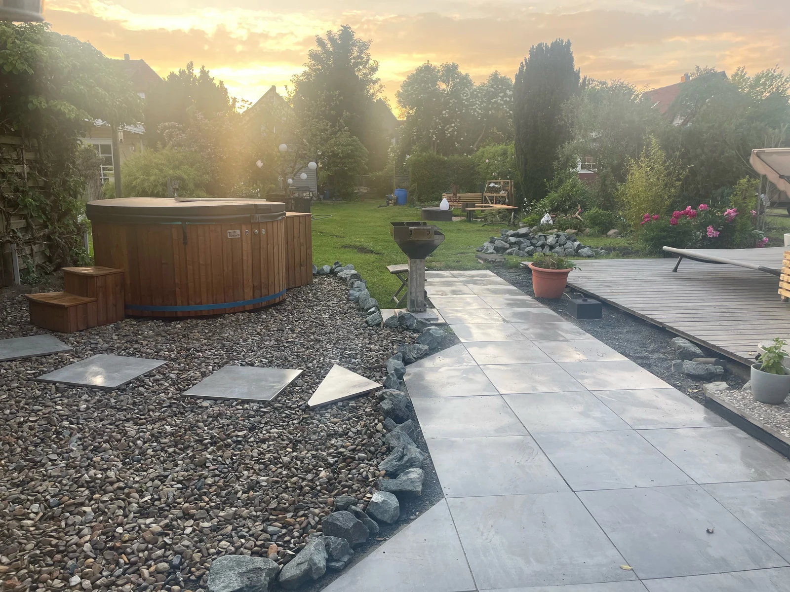 Houten hottub in een aangelegde tuin bij avondlicht