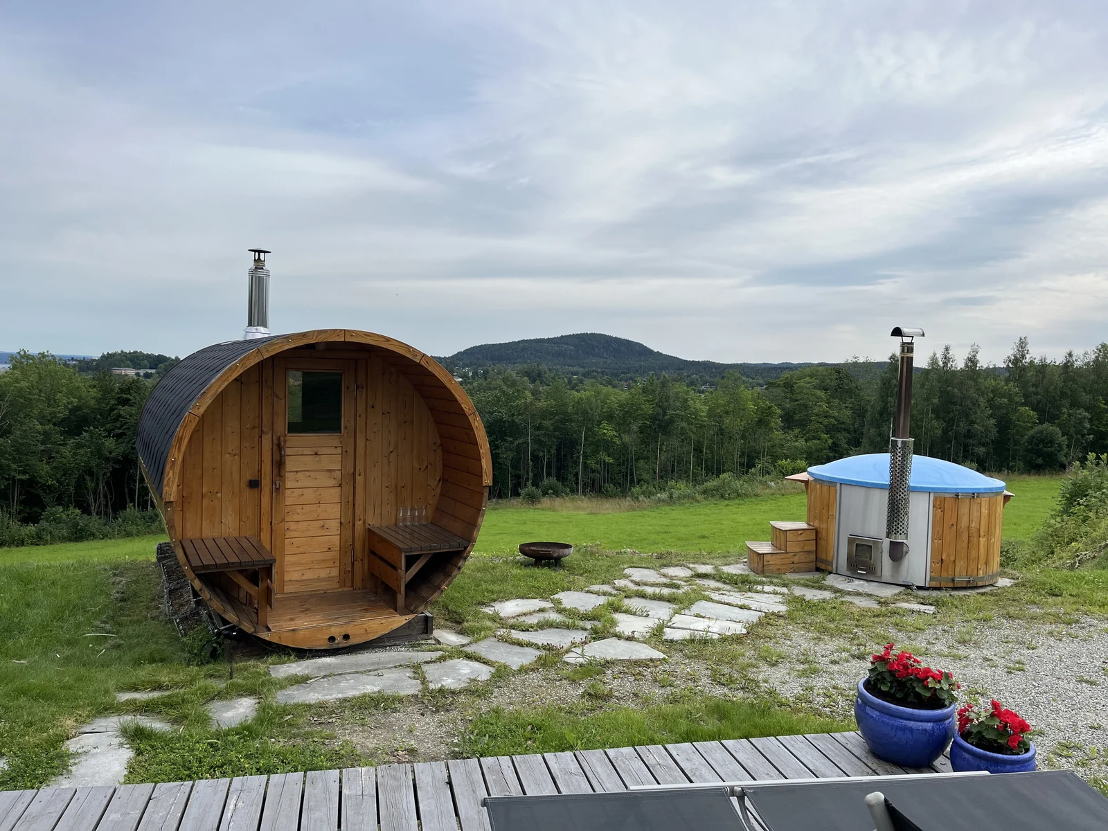 Houten barrel sauna en aparte hottub in een groene tuin
