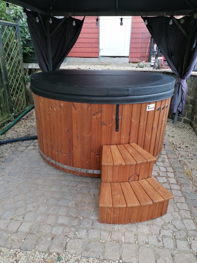 Houten TimberIN-hottub met afdekking en trap onder een tuinpaviljoen