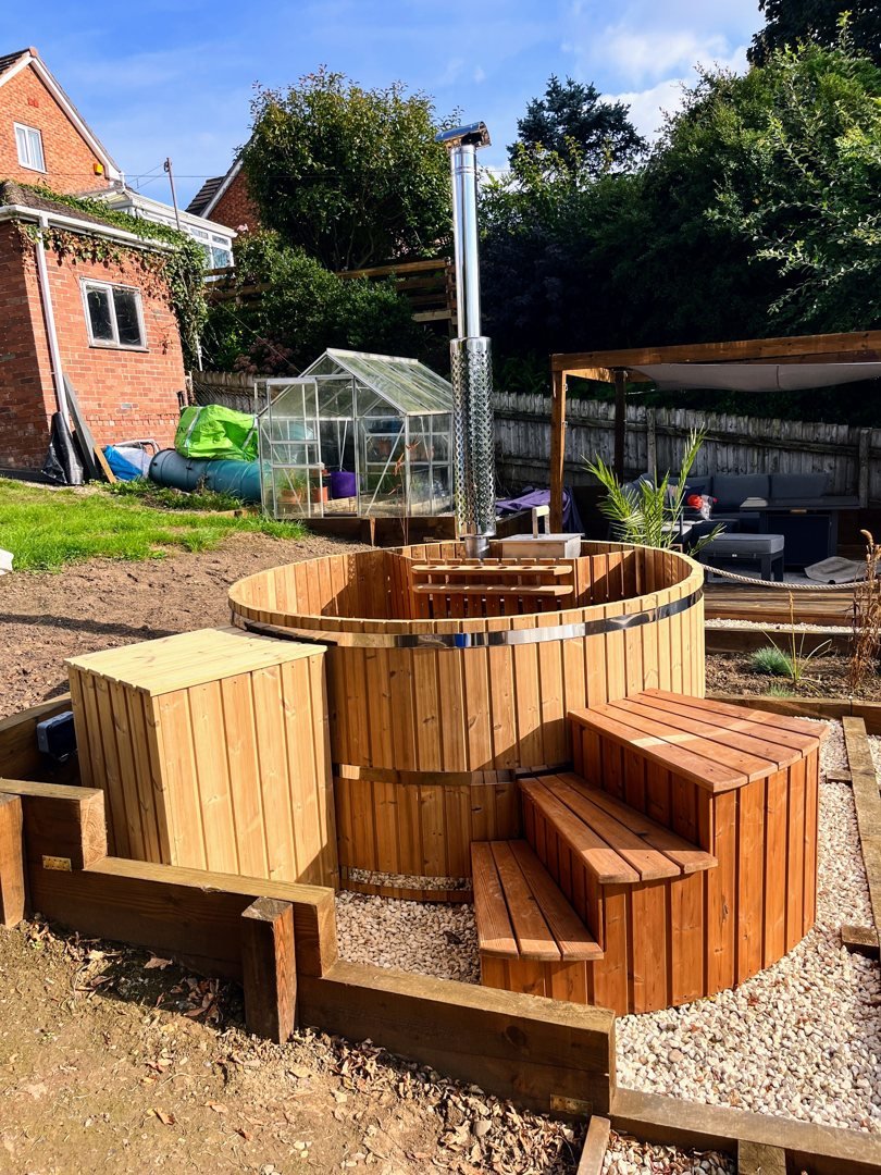 Houten hottub met interne houtkachel en trap in de tuin