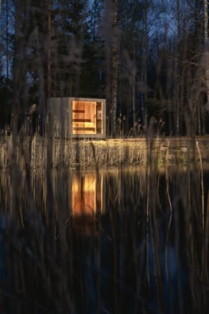 TimberIN Nordic Cube verlicht in de nacht tussen het riet